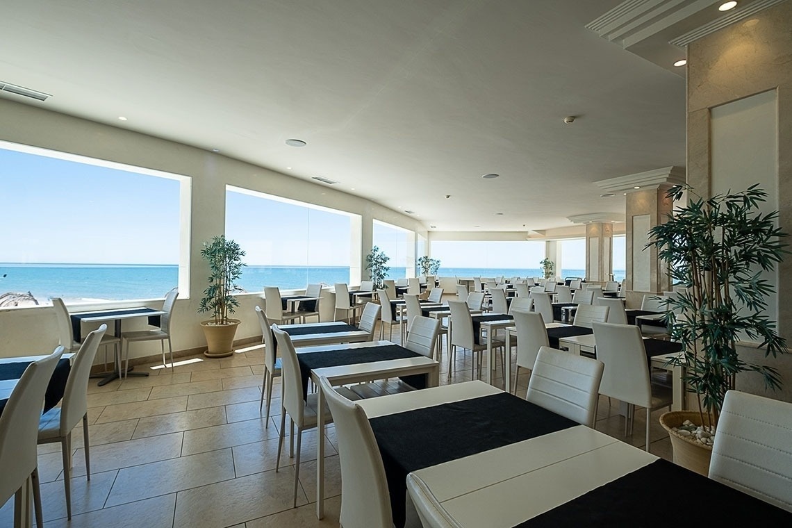 tables and chairs in a restaurant with a view of the ocean