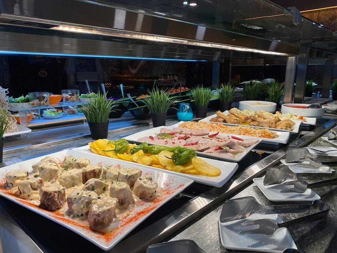 a buffet line with plates of food including meat and potatoes