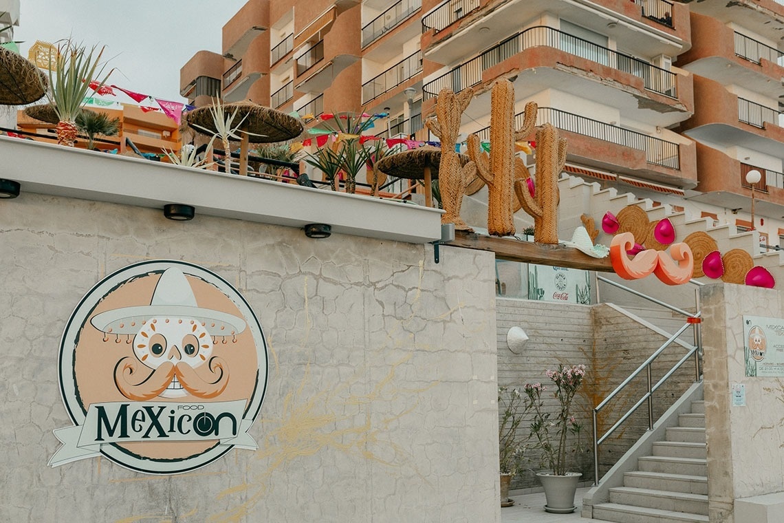 a mexican food menu sits on a table in front of a beach