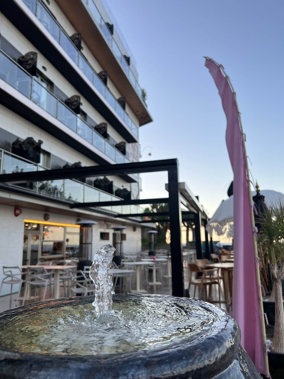 a fountain in front of a building with tables and chairs
