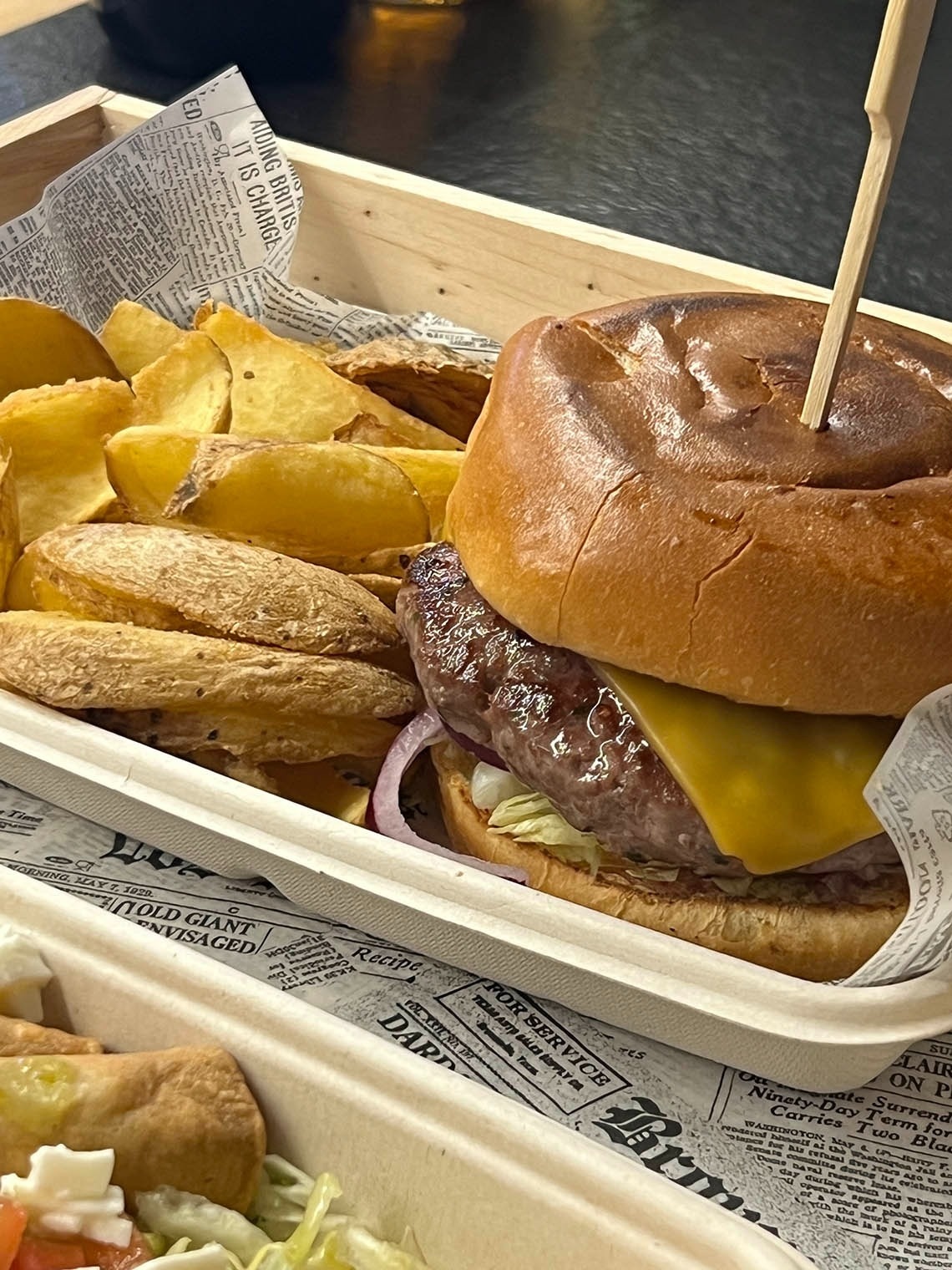 a hamburger with a toothpick sticking out of it is in a container with french fries