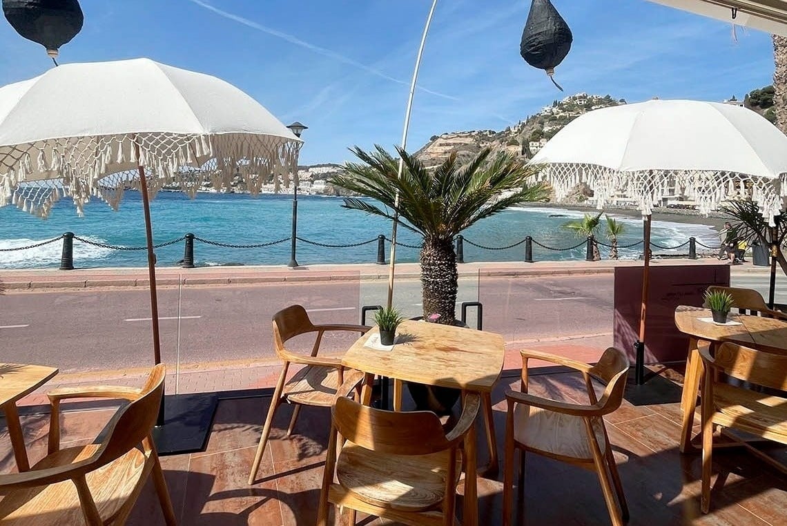 a view of the ocean from a restaurant with tables and chairs