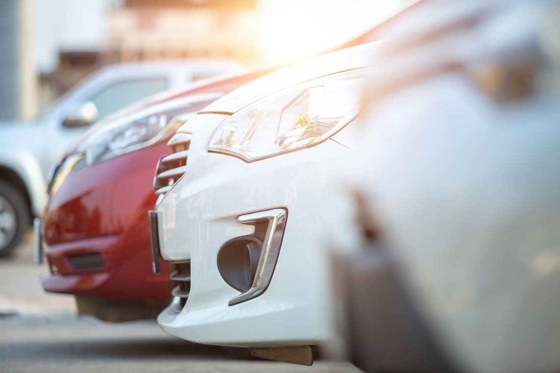 una fila de autos rojos y blancos están estacionados uno al lado del otro