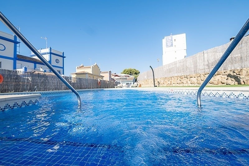 una piscina con un edificio azul y blanco en el fondo