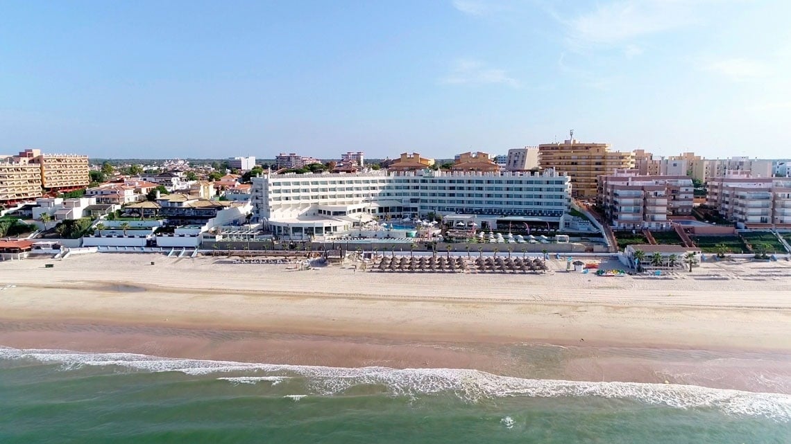 an aerial view of a beach with a hotel in the background