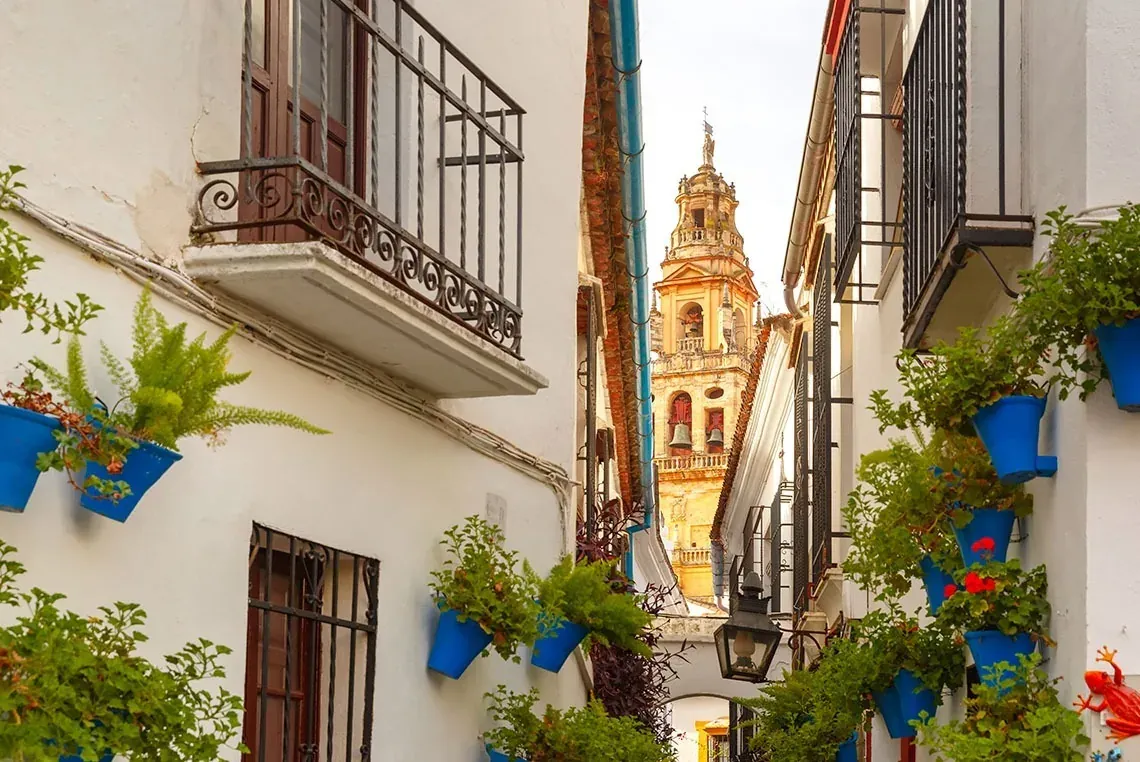 Callejón andaluz con flores y torre campanario, ideal para tu estancia On Hotels: ON Corporativa.