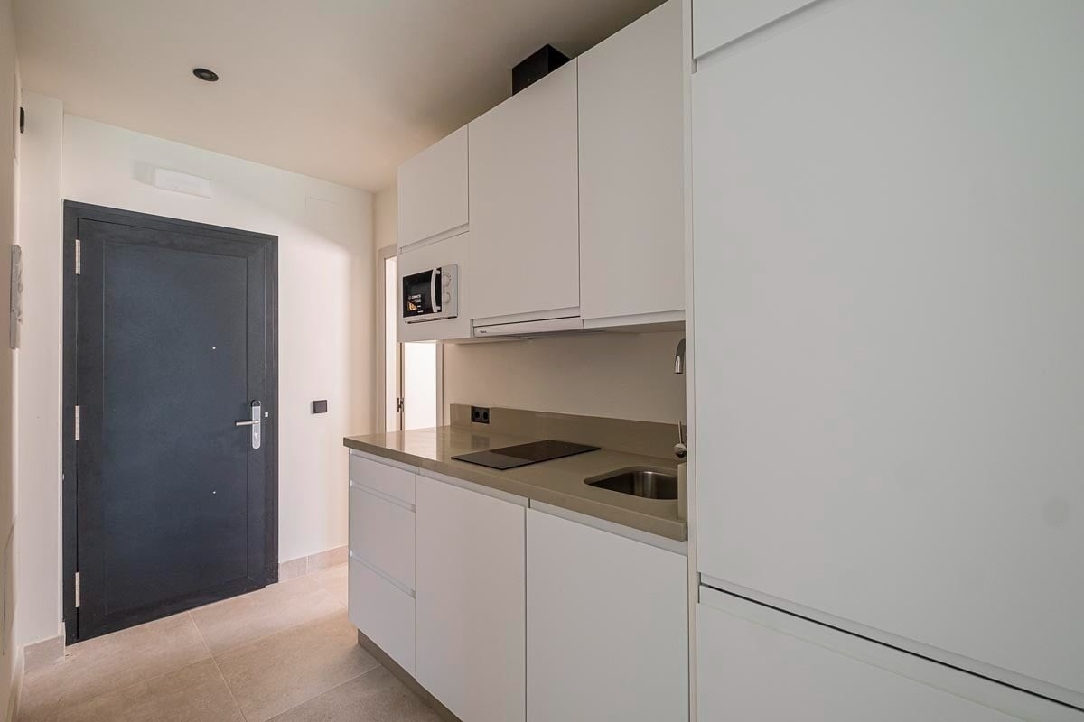 una pequeña cocina con gabinetes blancos y un microondas