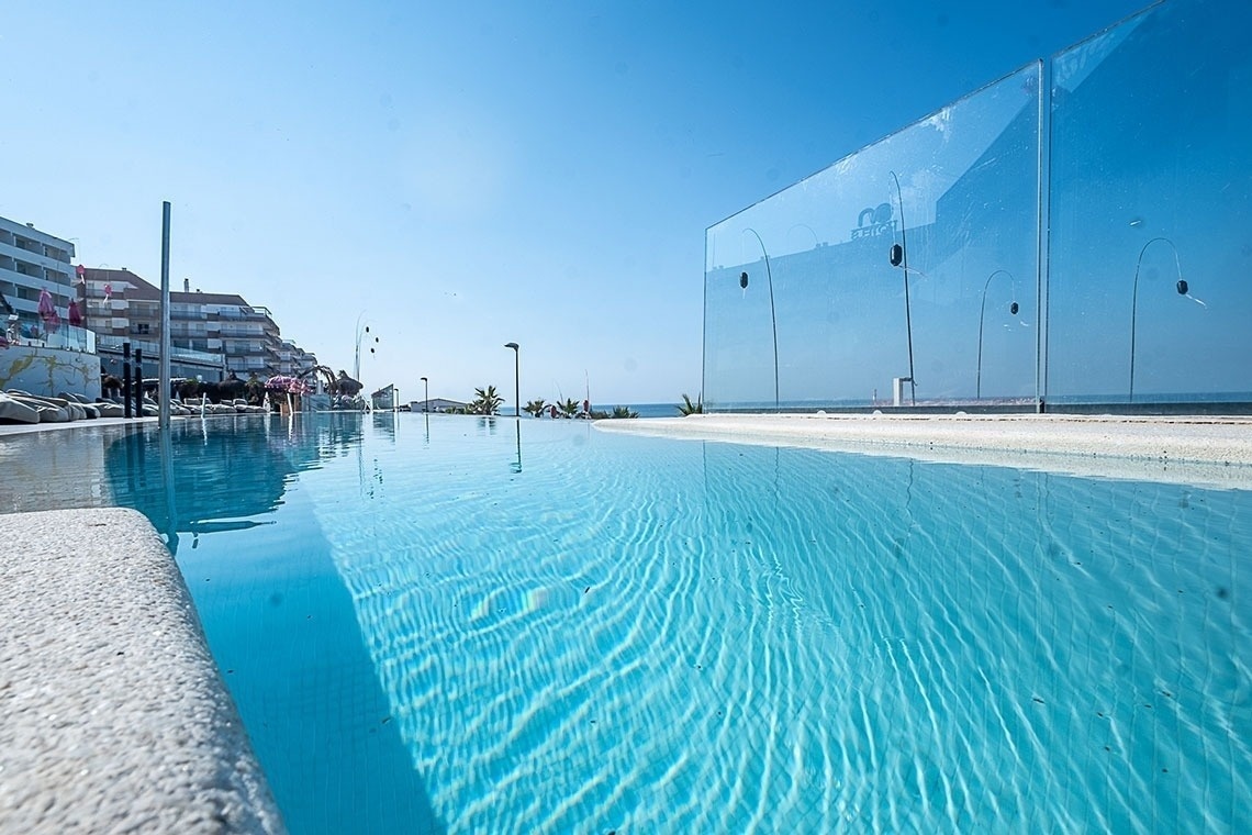 una piscina infinita está rodeada de una valla de vidrio transparente