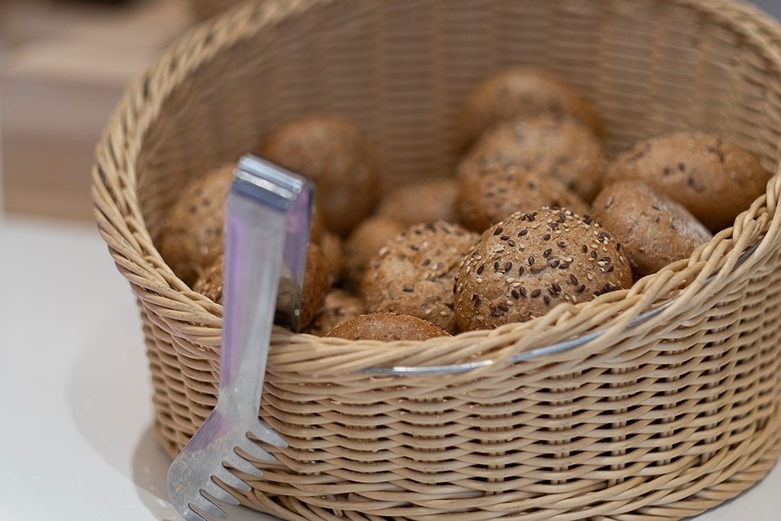 a wicker basket filled with bread rolls and tongs