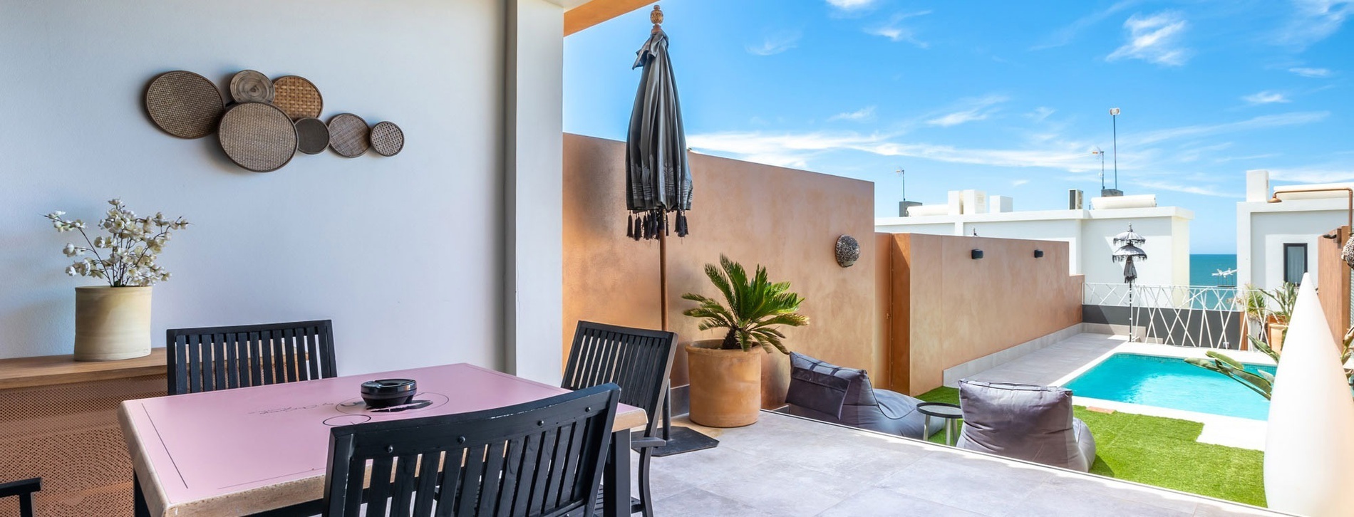 un balcon avec une table et des chaises et une piscine en arrière-plan