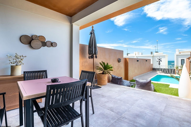 un patio avec une table et des chaises et une piscine en arrière-plan