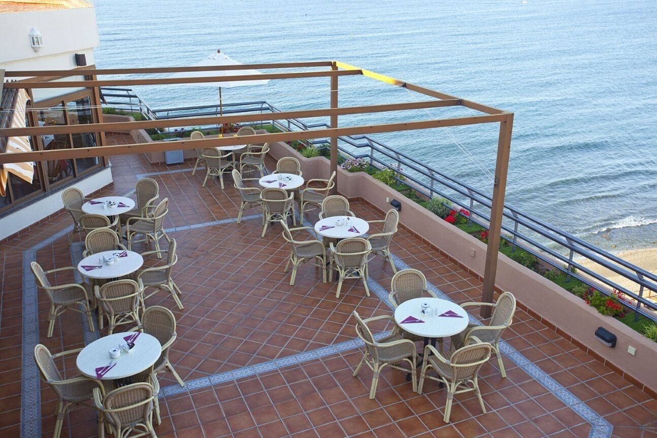 a patio with tables and chairs overlooking the ocean