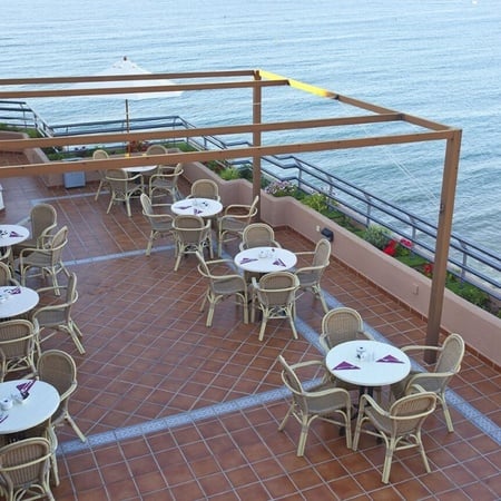 a patio with tables and chairs overlooking the ocean
