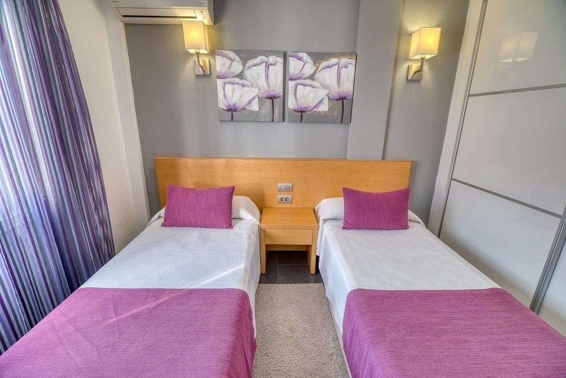 a bedroom with two twin beds and purple pillows