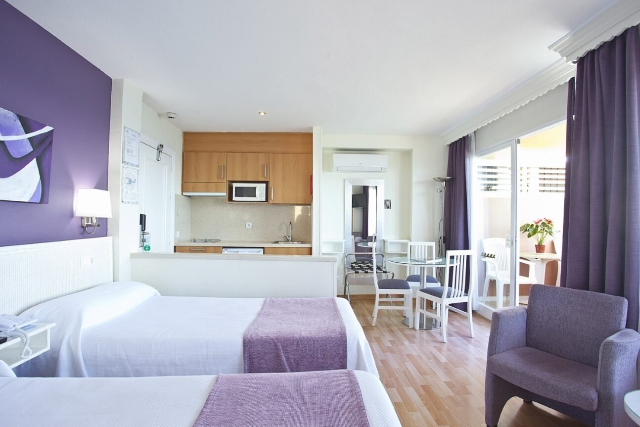a hotel room with two beds and purple curtains