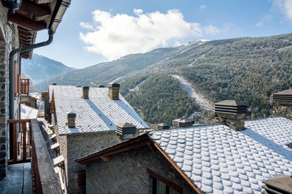 ein schneebedecktes Dach eines Gebäudes mit Blick auf die Berge