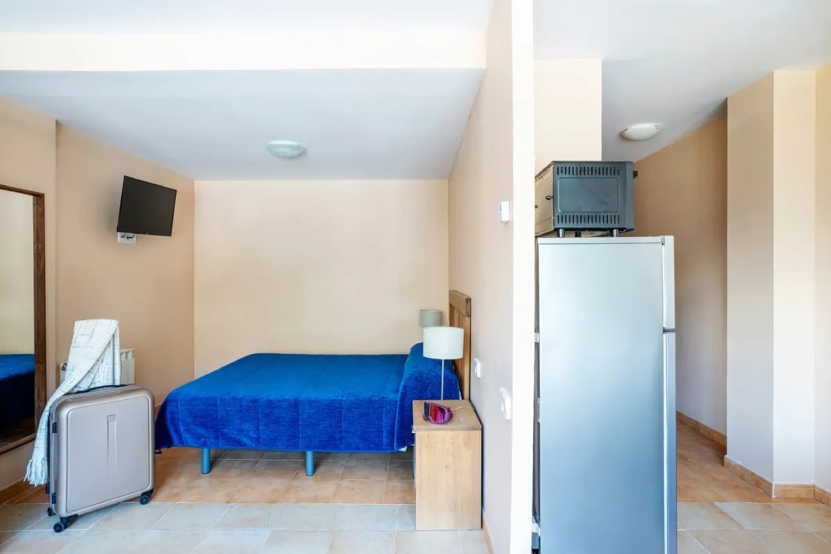 une chambre avec un lit bleu et un réfrigérateur
