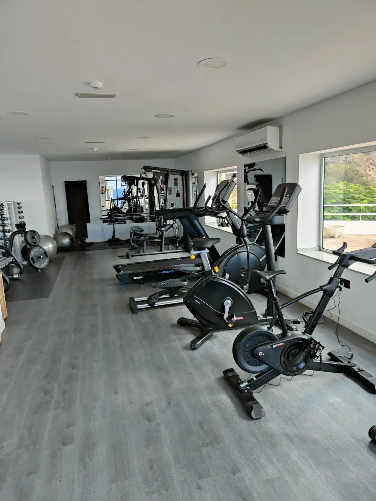 ein Fitnessstudio mit vielen Geräten und einem großen Spiegel
