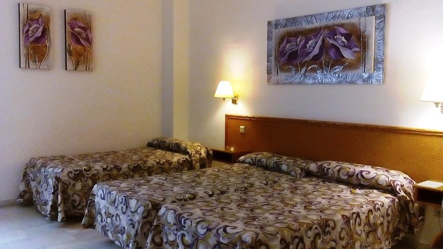 une chambre d' hôtel avec trois lits et trois peintures sur le mur