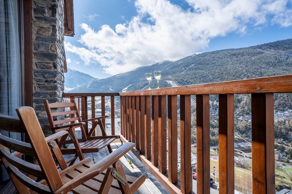 Zwei Holzstühle stehen auf einem Balkon mit Blick auf die Berge