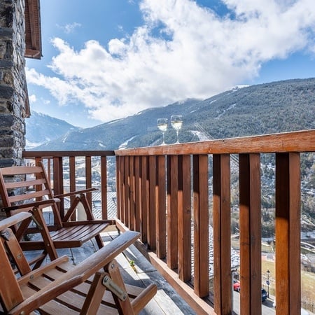 two wooden chairs on a balcony overlooking mountains