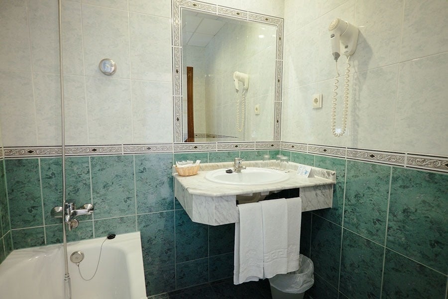 a bathroom with green and white tiles and a sink