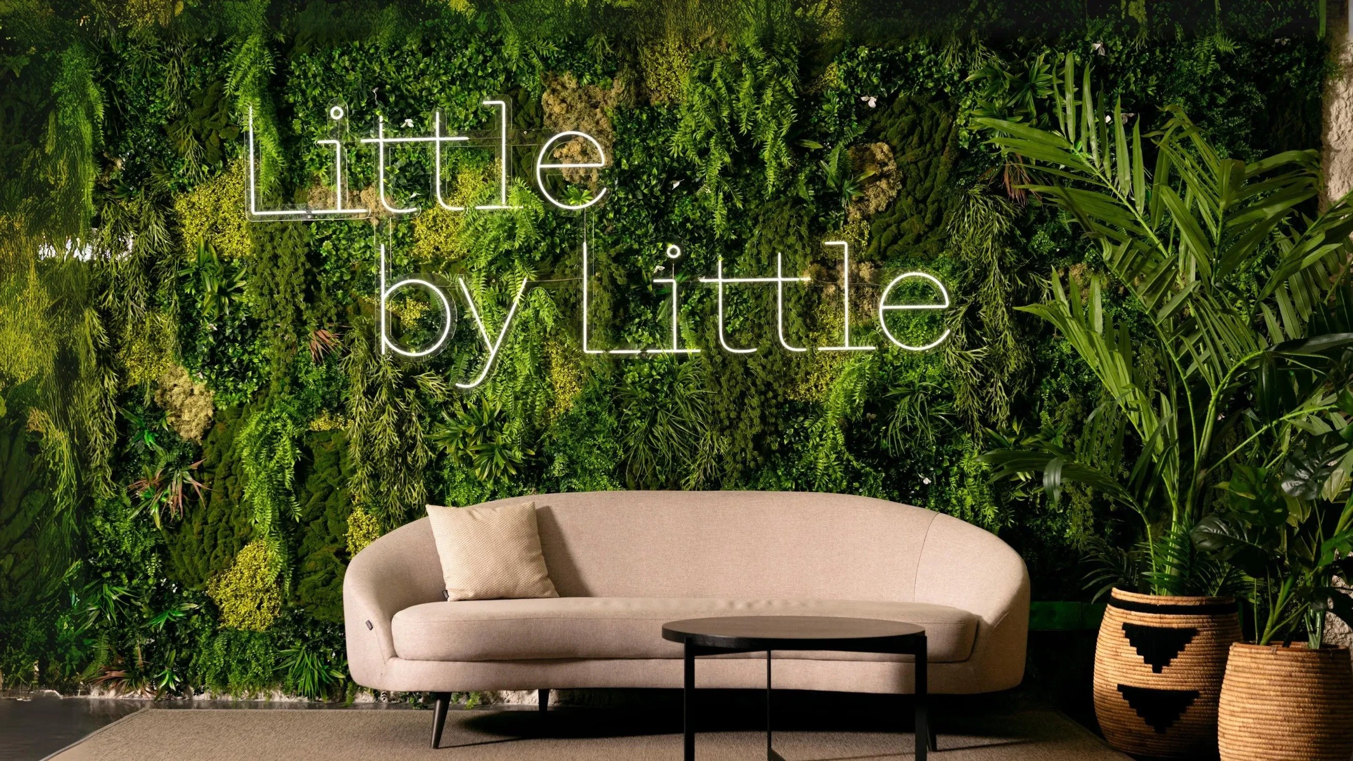 ein Wohnzimmer mit einer Couch und einem Tisch und einer Wand mit der Aufschrift " little by little "
