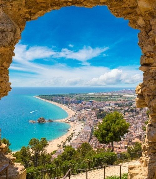 a view of a beach and city from a stone archway