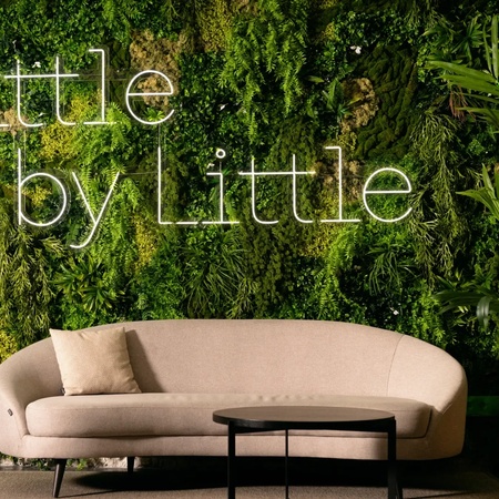 a couch in front of a wall that says little by little