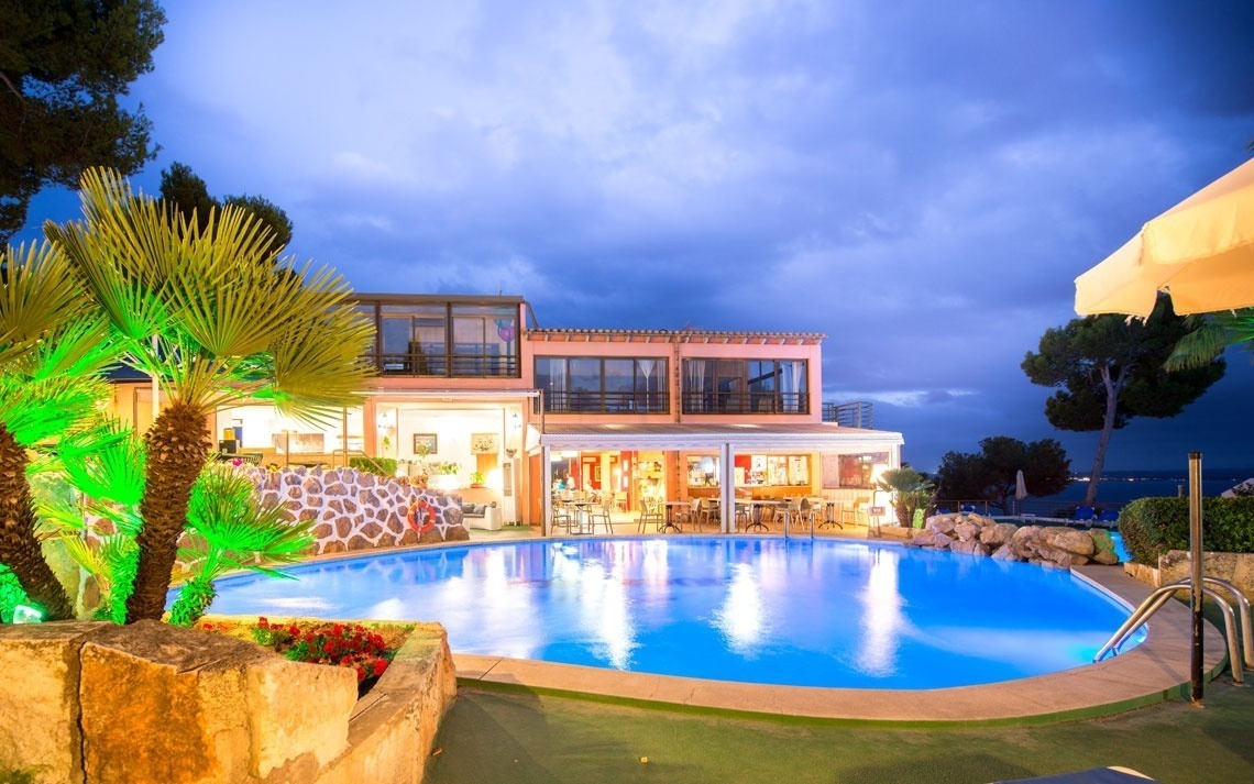 Panorámica de piscina exterior y facilidades del hotel Ona Aucanada al anochecer
