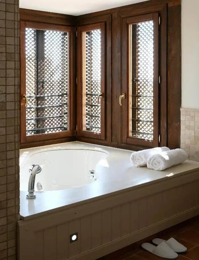a bathtub in a bathroom with two windows behind it