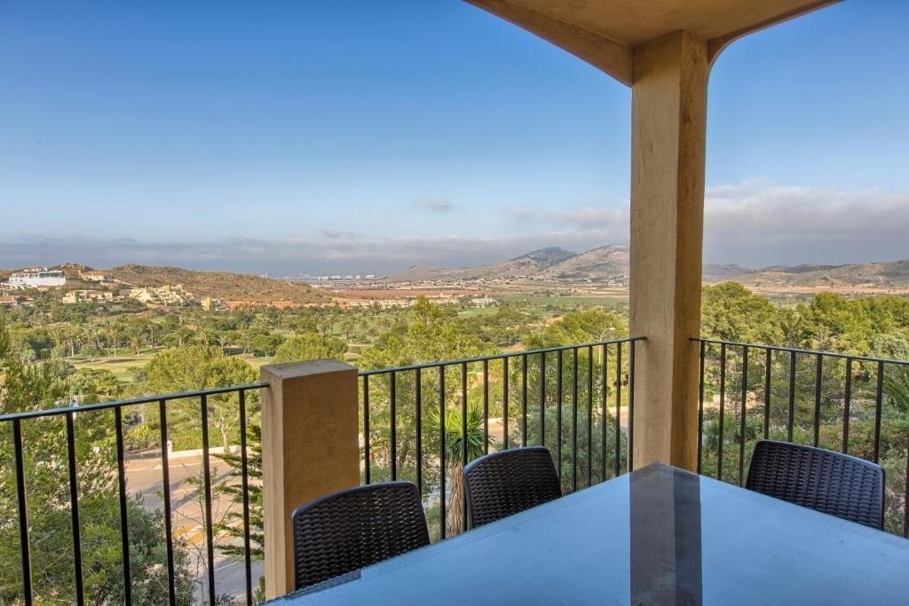 une table et des chaises sur un balcon avec une vue sur les montagnes