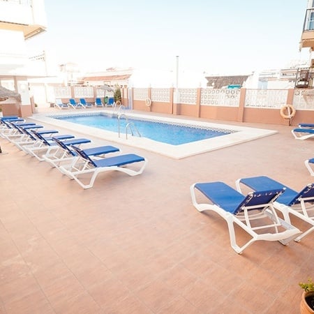 Liegestühle und Sonnenschirme umgeben einen großen Swimmingpool