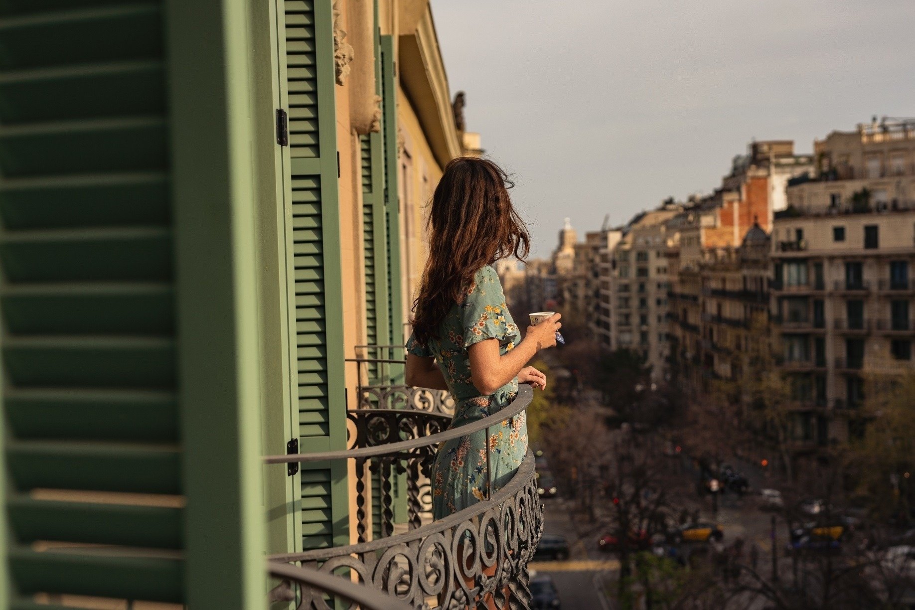 Woman drinking coffee from a balcony of the Hotel Boutique Mosaic by Ona Hotels, in Barcelona