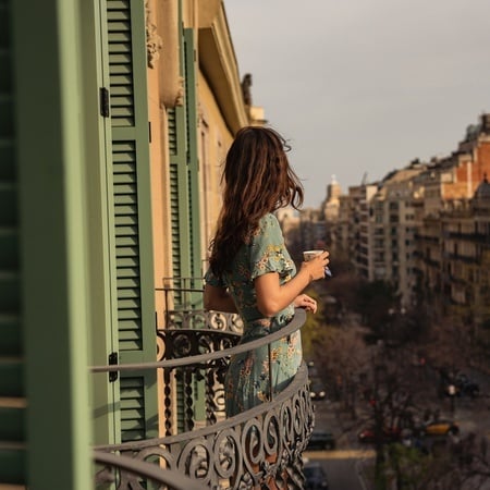 Frau trinkt Kaffee von einem Balkon des Hotel Boutique Mosaic by Ona Hotels in Barcelona