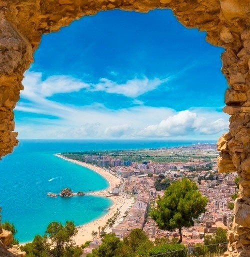 una vista del océano y una ciudad a través de un arco de piedra