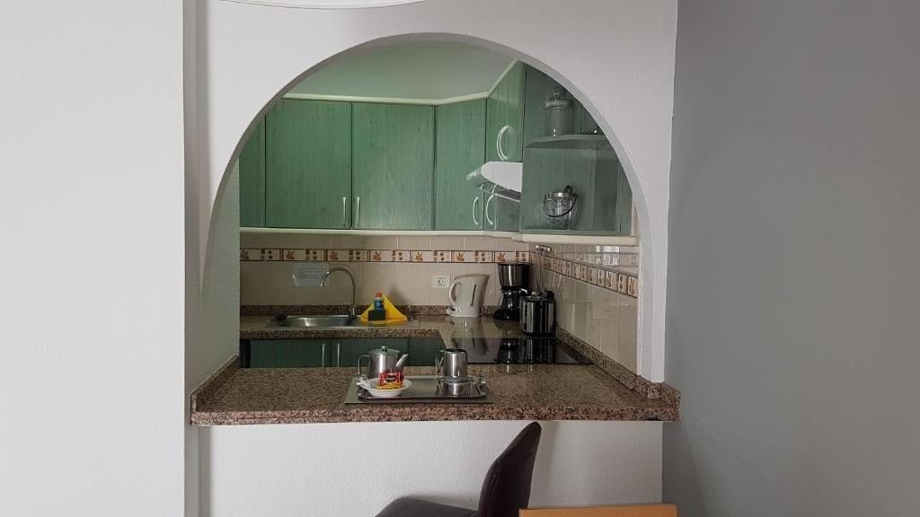 une cuisine avec des armoires vertes et un comptoir en granit