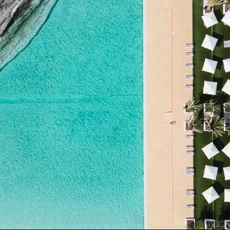 an aerial view of a swimming pool with white umbrellas