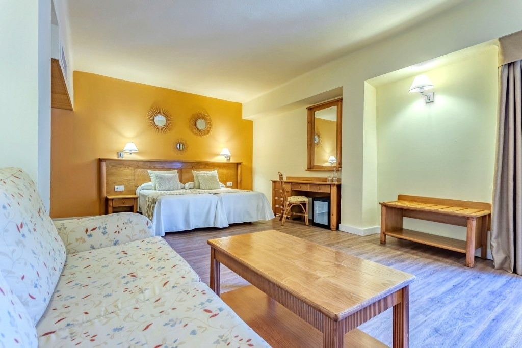 una habitación con dos camas y una mesa de madera