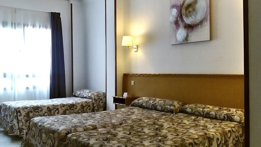 ein Hotelzimmer mit drei Betten und einem Gemälde an der Wand