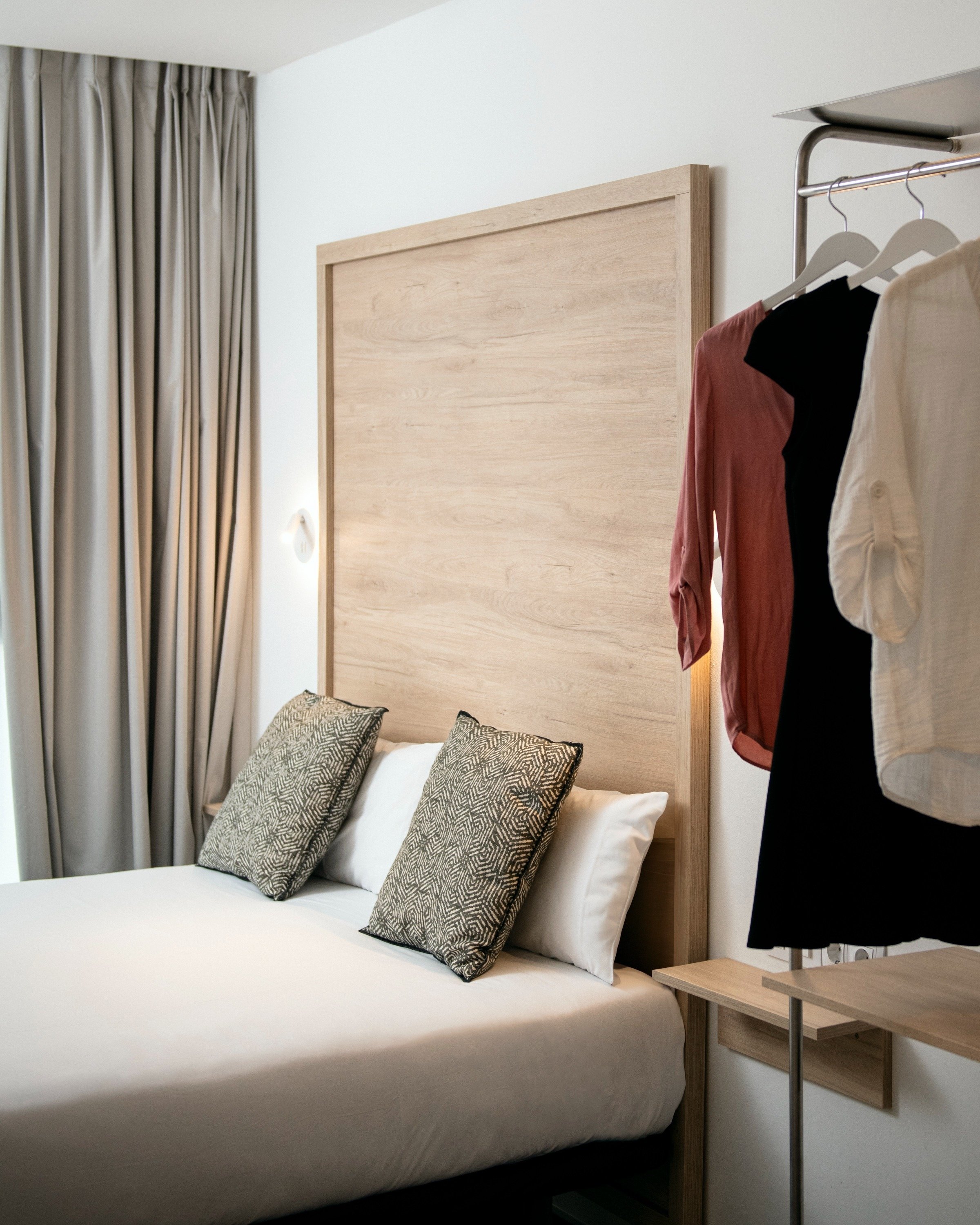 a bedroom with a bed and clothes hanging on a rack