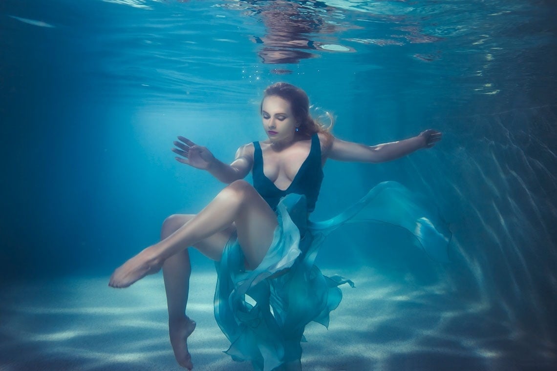 una mujer con un vestido azul está nadando bajo el agua