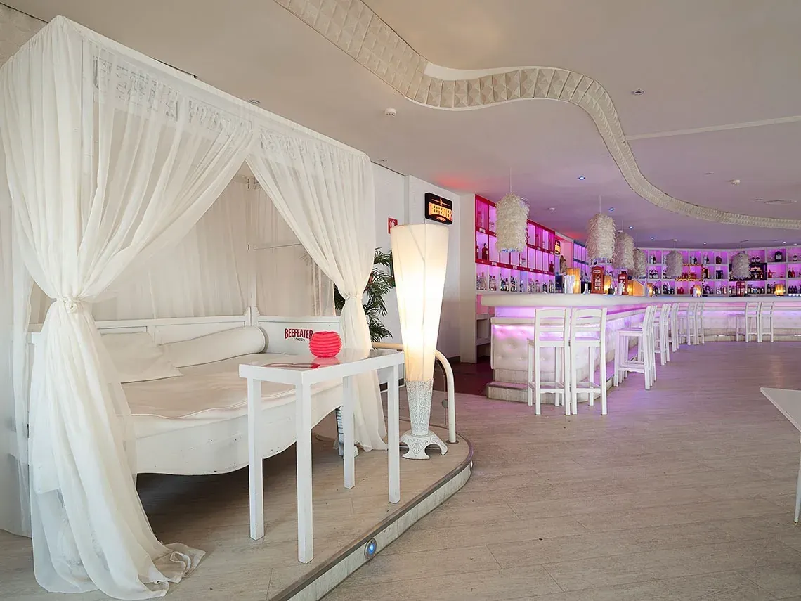 Lujoso salón VIP de hotel On Corporativa con camas balinesas y barra de bar iluminada.