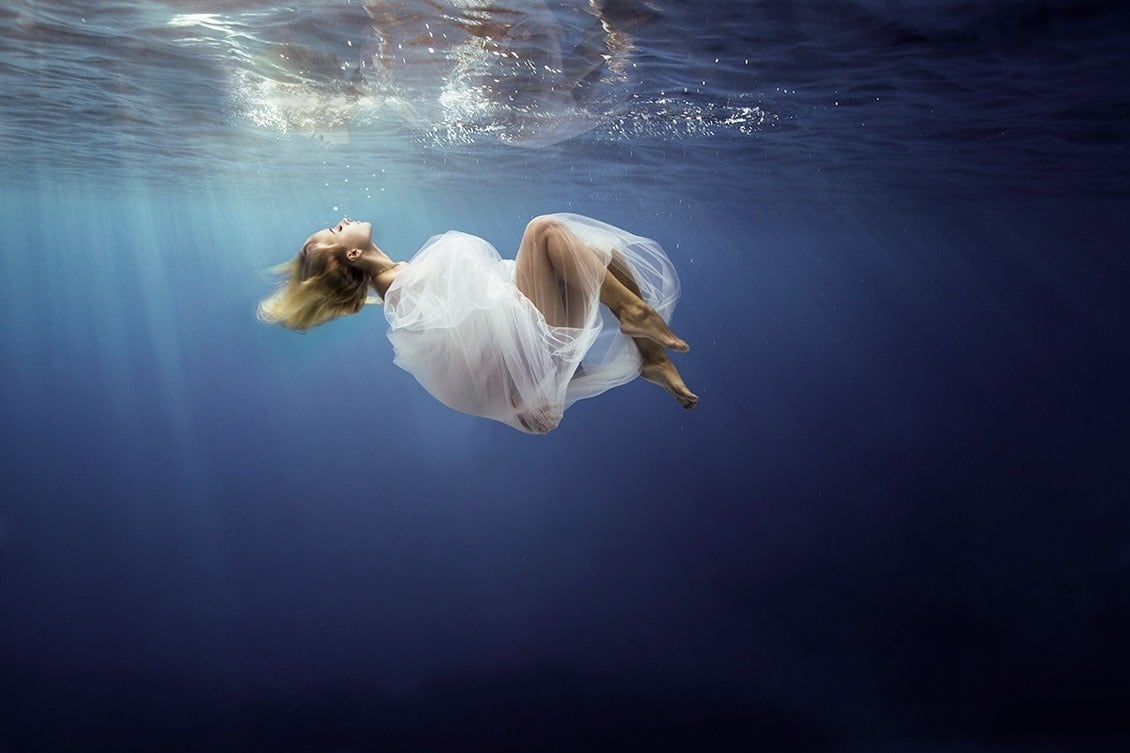 une femme en robe blanche flotte sous l' eau