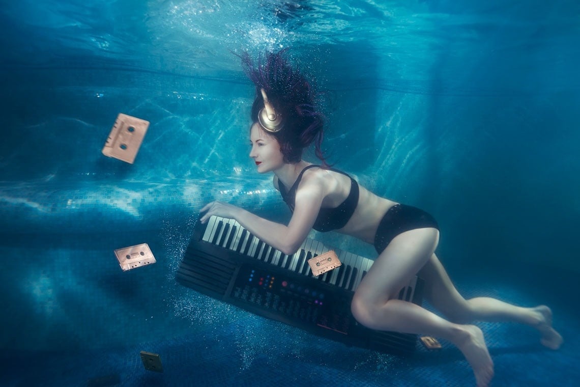 a woman in a bikini is underwater holding a keyboard