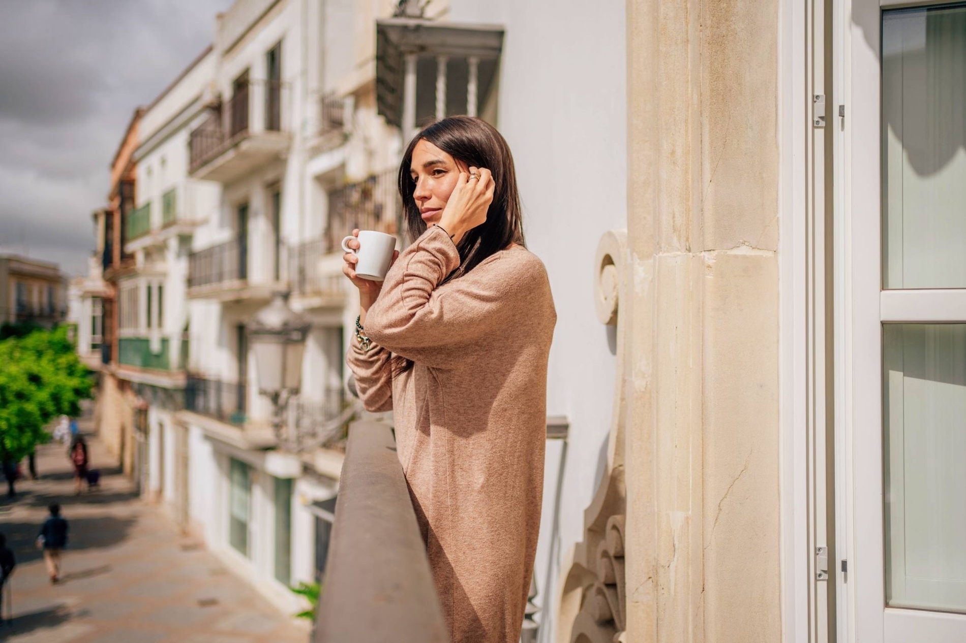 a woman standing on a balcony holding a cup of coffee