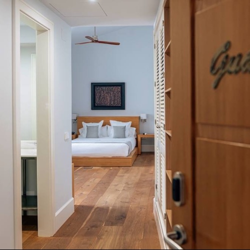una puerta de madera conduce a una habitación con una cama y un ventilador de techo
