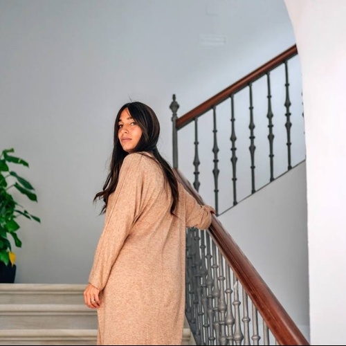una mujer con un suéter marrón camina por las escaleras