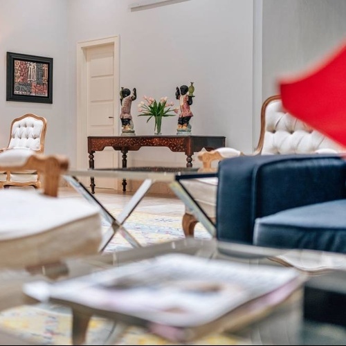 a living room with a blue couch and white chairs