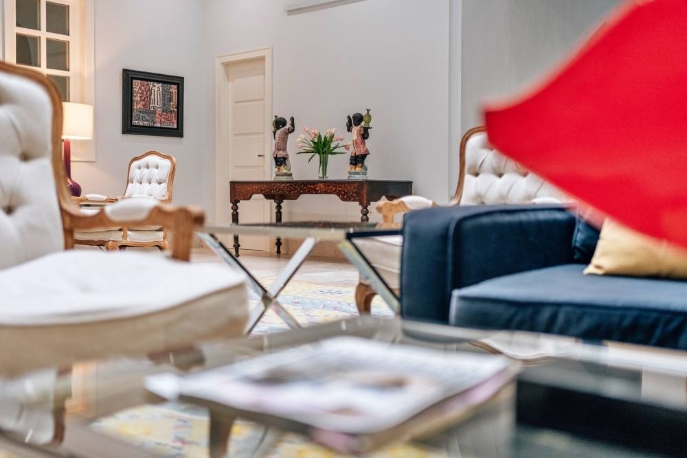 a living room with a blue couch and white chairs